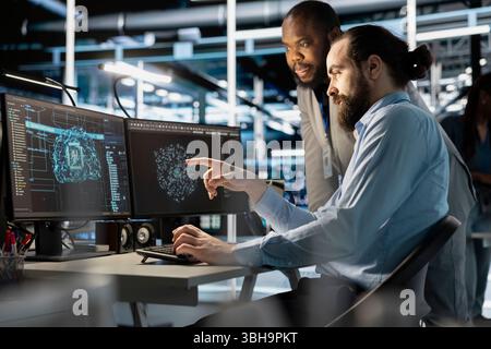 Équipe de techniciens utilisant un PC dans un centre de données, intégrant des outils d'automatisation pilotés par l'IA, faisant de la maintenance. Des collègues de ferme de serveurs utilisant des modèles d'apprentissage automatique d'intelligence artificielle Banque D'Images