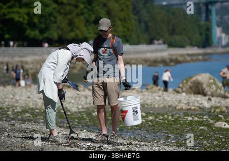 Vancouver, Canada. 8 juin 2025. Des bénévoles ramassent des ordures lors d’un événement de nettoyage des rives lors de la Journée mondiale des océans au parc Stanley à Vancouver, Colombie-Britannique, Canada, le 8 juin 2025. Le 8 juin marquait la Journée mondiale des océans. Des bénévoles ont pris part à un événement de nettoyage du rivage, ramassant les ordures le long du rivage pour sensibiliser la population à la protection de l’environnement marin. Crédit : Liang Sen/Xinhua/Alamy Live News Banque D'Images