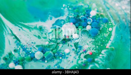 Émulsion goutte à goutte. Bulle de peinture à l'huile. Flux de boule acrylique coloré dans le liquide vert. Les particules bleu FIZZ d'art wave mélangent un arrière-plan défocalisé abstrait. Banque D'Images