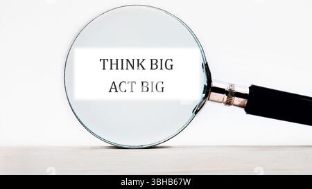 PENSEZ BIG ACT GRANDS mots conceptuels concentrés à l'aide d'une loupe. Banque D'Images