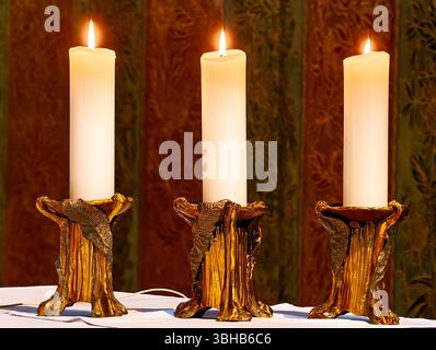 Trois bougies brûlantes dans des supports artistiques - bougie chaude et brillante avec des stands d'or élégants sur fond décoratif, atmosphère paisible et spirituelle Banque D'Images