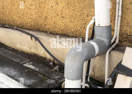 Le tuyau est fixé à un mur. Le tuyau est blanc et gris. Le mur est bronzé Banque D'Images