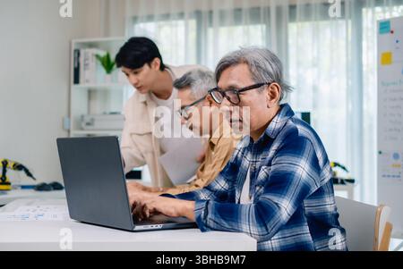 Groupe de senior asiatique dans un développement logiciel collaboratif analysant des organigrammes lors d'une formation bootcamp Banque D'Images