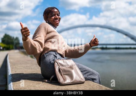 Jeune femme noire joyeuse profitant d'une journée ensoleillée dans la ville. Banque D'Images