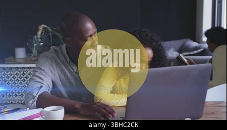 Image de cercles jaunes sur l'homme afro-américain et sa fille à l'aide d'un ordinateur portable ensemble Banque D'Images