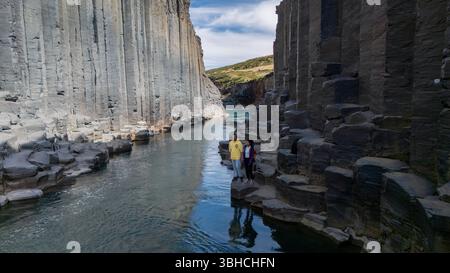 Explorez le magnifique canyon Studlagil en Islande, où d'imposantes colonnes de basalte s'élèvent de façon spectaculaire le long d'une rivière sereine. Les visiteurs peuvent admirer la beauté naturelle et les formations géologiques uniques. Banque D'Images
