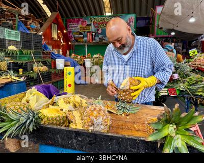 Vendeur coupant des ananas, Mercado Jamaica, l’un des marchés publics traditionnels de Mexico. CDMX, Mexique Banque D'Images