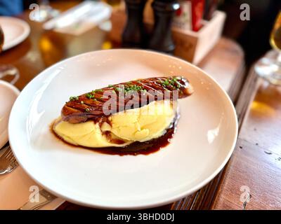 Saucisses grillées avec purée de pommes de terre et ciboulette dans un pub rustique prêt à manger Banque D'Images