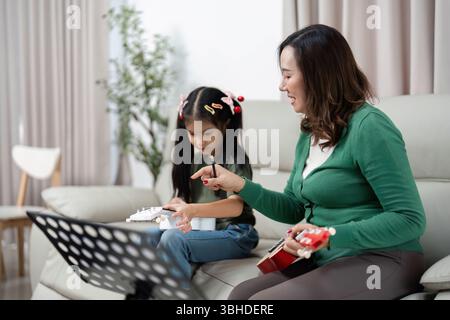 Interaction musicale. Mère et fille jouant des instruments ensemble à la maison. Banque D'Images