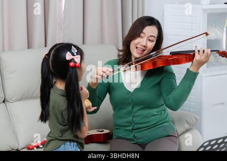 Interaction musicale. Mère et fille aiment jouer du violon ensemble à la maison. Banque D'Images