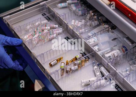 LK Osnabrück, Deutschland 30. Januar 2023 : Im Bild : Dieses Bild zeigt eine geöffnete Schublade eines medizinischen Notfallwagens oder Medikamentenschranks, die eine hochorganisierte Anordnung von lebenswichtigen Medikamentenampullen und kleineren Infusionsflaschen offenbart. Die Schublade ist mit transparenten Facheinteilungen versehen, die eine saubere Trennung und schnelle Auffindbarkeit der verschiedenen Arzneimittel ermöglichen. Deutlich erkennbar sind diverse Ampullen mit klaren oder bräunlichen Flüssigkeiten sowie kleinere, vorgefüllte Infusionsbeutel. Spezifische Schriftzüge wie ATROPIN Banque D'Images