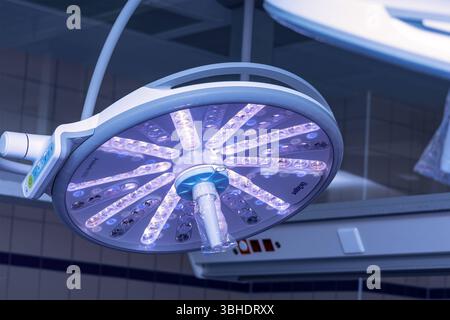 LK Osnabrück, Deutschland 30. Januar 2023 : Im Bild : Dieses Bild zeigt eine hochmoderne Operationslampe, die éminent im Vordergrund an der Decke eines sterilen medizinischen Raumes befestigt ist. Die runde OP-Leuchte ist mit zahlreichen einzelnen LED-Modulen ausgestattet, die ein klares, präzises und leicht violett schimmerndes Licht abgeben idéal für die optimale Ausleuchtung des Operationsfeldes. IM Hintergrund sind weitere Elemente der Deckenkonstruktion sowie diffuse Lichtquellen und möglicherweise zusätzliche medizinische Geräte oder Anlagen erkennbar, die die komplexe Infrastruktur eine Banque D'Images