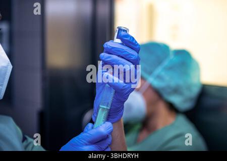 LK Osnabrück, Deutschland 30. Januar 2023 : Im Bild : dieses Bild fängt einen entscheidenden moment in einem Operationssaal eines Krankenhauses ein : Ein Anästhesist, erkennbar an seinen blauen Einweghandschuhen, ist dabei, mit einer Spritze ein Medikament aufzuziehen. Diese präzise Vorbereitung ist Teil der Narkose und Schmerztherapie, die dem Patienten während des chirurgischen Eingriffs zukommen wird. Die Hände Halten die Spritze und möglicherweise eine Medikamentenampulle mit höchster Sorgfalt und Konzentration. I Die Szene symbolisiert die Verantwortung und expertise des Anästhesisten im GES Banque D'Images