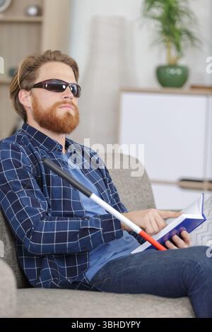 aveugle lisant le livre écrit en braille sur le canapé Banque D'Images