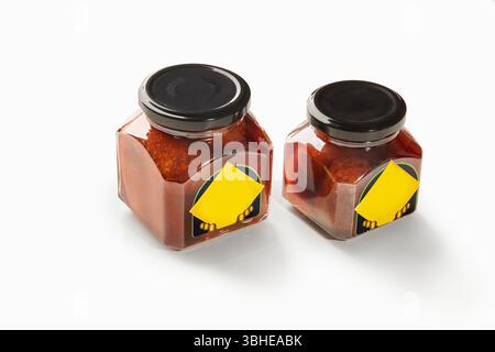 Deux pots de baba al rhum montrant des cerises conservées dans du sirop de rhum sur fond blanc Banque D'Images