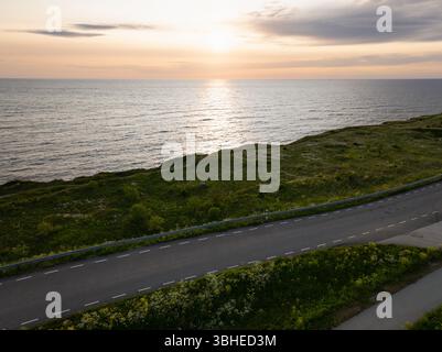 Vue aérienne d'une route panoramique le long de la côte de la mer Baltique en Estonie pendant l'heure dorée. Paysage du soir d'été dans les rayons du coucher du soleil. Banque D'Images