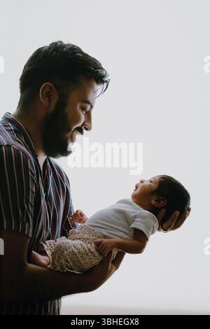 Père tenant la fille nouveau-née dans l'étreinte d'amour avec un contre-jour doux Banque D'Images