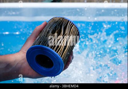 Cartouche filtrante de remplacement sale de piscine dans la main d'un homme sur fond d'éclaboussure d'eau. Concept de qualité de l'eau de piscine. Copier l'espace. Banque D'Images