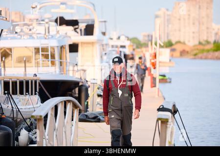 Russie, St.Petersburg, 08 juin 2025 : un yachtsman marche le long de la jetée, Un yacht club au coucher du soleil, des yachts et des voiliers sont amarrés aux couchettes, énorme Banque D'Images