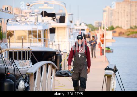 Russie, St.Petersburg, 08 juin 2025 : un yachtsman marche le long de la jetée, Un yacht club au coucher du soleil, des yachts et des voiliers sont amarrés aux couchettes, énorme Banque D'Images