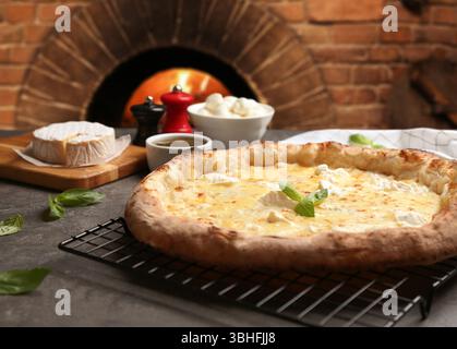 Délicieuse pizza au fromage chaud et ingrédients sur la table grise contre le four Banque D'Images