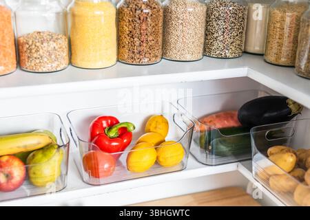 petit garde-manger organisé avec des bocaux transparents assortis remplis de céréales, légumineuses, épices et produits frais dans des récipients, alimentation saine, maison rangée, organi Banque D'Images