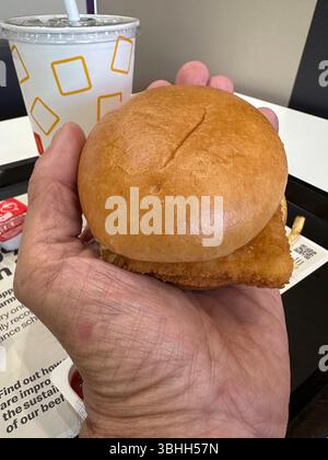 minuscule hamburger de poisson de la célèbre chaîne de restaurants fast foot tenu dans la paume de la main pour l'échelle montrant sa taille réduite portsmouth angleterre royaume-uni Banque D'Images