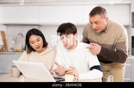 Une famille amicale regarde quelque chose ensemble sur Internet ou des chats vidéo via un ordinateur portable Banque D'Images