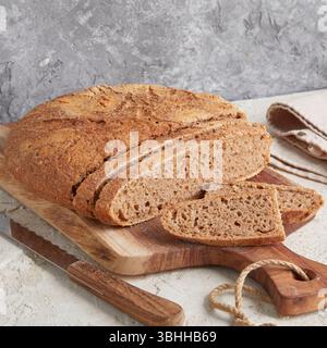 Pain d'épeautre entier sur planche de bois - un pain artisanal rustique et riche en fibres, parfait pour manger propre, petit déjeuner ou prendre des photos saines de style boulangerie Banque D'Images