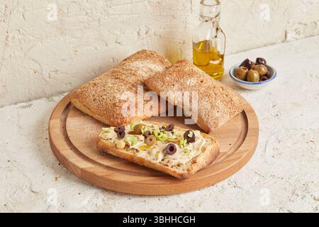 Ciabatta d'épeautre sur une surface en bois avec des olives et de l'huile d'olive en arrière-plan - un pain rustique de style méditerranéen, parfait pour l'apéritif. Banque D'Images