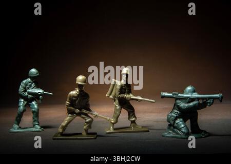 Quatre figurines de soldat miniatures positionnées dans une impasse tendue, présentant diverses positions de combat Banque D'Images