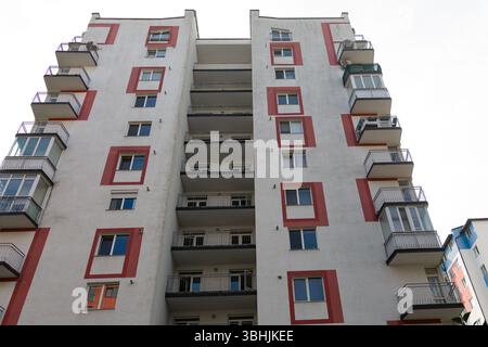 Un grand bâtiment résidentiel se dresse en évidence, avec des accents colorés et de nombreux balcons. La structure reflète la vie urbaine contemporaine dans Banque D'Images