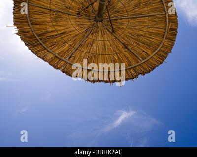 Regardant vers le haut du parasol rustique avec le ciel clair et les nuages blancs doux stries. Sensation tropicale naturelle avec espace centré pour les superpositions de texte Banque D'Images