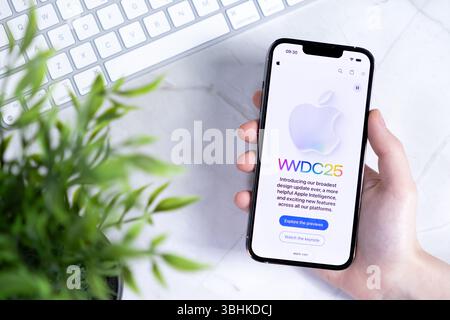 Poznan, Pologne - 10 juin 2025 : gros plan d'une main tenant un iPhone Apple montrant le site WWDC25 avec le nouveau iOS 26 et Liquid Glass dans le design Banque D'Images