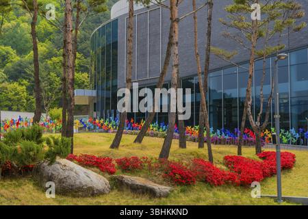 Muju, Corée du Sud. 1er mai 2019 : arbres, fleurs et roues à épingles devant la vitre extérieure du Musée National de Taekwondo Banque D'Images