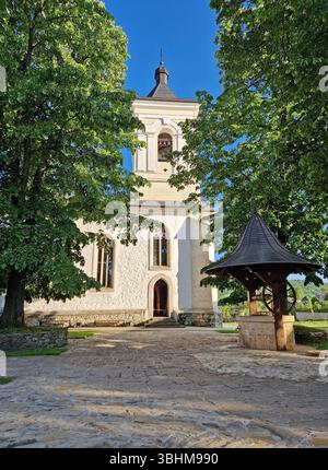 Vieux puits traditionnel en bois et pierre et le clocher entouré de vieux chênes dans la cour du monastère de Capriana, République de Moldavie Banque D'Images