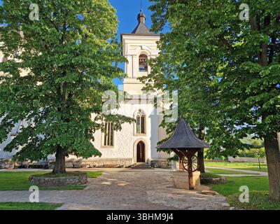 Vieux puits traditionnel en bois et pierre et le clocher entouré de vieux chênes dans la cour du monastère de Capriana, République de Moldavie Banque D'Images