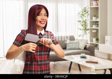 Jeune femme asiatique se brossant les cheveux à la maison Banque D'Images