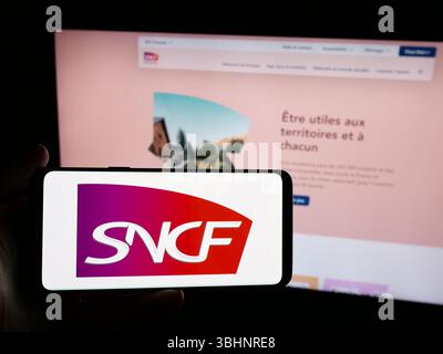 Stuttgart, Allemagne - 03-20-03 2025 : personne tenant un smartphone avec le logo de la compagnie ferroviaire française SNCF Group sur l'écran devant le site. Banque D'Images
