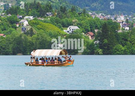 Touristes appréciant une promenade traditionnelle en bateau de pletna en bois sur le lac de Bled, Slovénie par une journée ensoleillée. Photo de haute qualité Banque D'Images