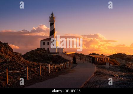 Coucher de soleil spectaculaire sur le phare de Favaritx et paysage côtier accidenté. Minorque Landmark, ciel saisissant, paysages des îles Baléares, Golden Hour Banque D'Images