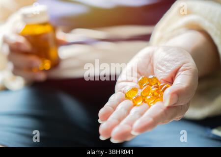 Une femme tient une bouteille d'huile de poisson et un récipient de pilules d'huile de poisson. Concept de soins de santé et de traitement. Mise au point sélective. Banque D'Images