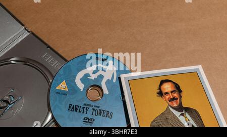Une boîte DVD ouverte de Fawlty Towers, avec un disque DVD et un livret présentant Basil Fawlty. Banque D'Images