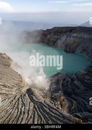 Vue aérienne par drone du sommet du cratère du mont Ijen émettant de la fumée de soufre du fond du cratère situé dans la zone de Banyuwangi, Java oriental, Indo Banque D'Images