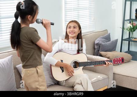 Session de musique mère et fille. Chanter et jouer de la guitare ensemble dans une atmosphère joyeuse. Banque D'Images