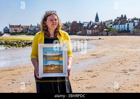 North Berwick, East Lothian, Écosse, Royaume-Uni, 11 juin 2025. Préparation pour l'exposition : L'artiste Jayne Stokes, spécialisée dans les peintures de paysages miniatures sur les « objets trouvés » tels que les boîtes d'allumettes, les vieilles boîtes de conserve ou la poterie de mer, se prépare pour l'ouverture de son exposition à Open Eye Gallery. L'exposition se concentre sur les peintures des Shetland : elle a reçu le prix VACMA Creative Scotland Artists Bursary Award pour y voyager cette année. Pic : Jayne avec un de ses tableaux sur la plage. Crédit : Sally Anderson/Alamy Live News Banque D'Images