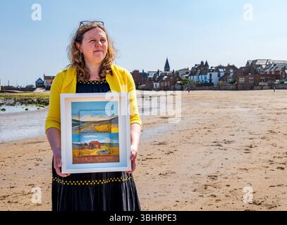 North Berwick, East Lothian, Écosse, Royaume-Uni, 11 juin 2025. Préparation pour l'exposition : L'artiste Jayne Stokes, spécialisée dans les peintures de paysages miniatures sur les « objets trouvés » tels que les boîtes d'allumettes, les vieilles boîtes de conserve ou la poterie de mer, se prépare pour l'ouverture de son exposition à Open Eye Gallery. L'exposition se concentre sur les peintures des Shetland : elle a reçu le prix VACMA Creative Scotland Artists Bursary Award pour y voyager cette année. Pic : Jayne avec un de ses tableaux sur la plage. Crédit : Sally Anderson/Alamy Live News Banque D'Images