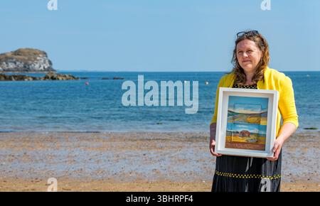 North Berwick, East Lothian, Écosse, Royaume-Uni, 11 juin 2025. Préparation pour l'exposition : L'artiste Jayne Stokes, spécialisée dans les peintures de paysages miniatures sur les « objets trouvés » tels que les boîtes d'allumettes, les vieilles boîtes de conserve ou la poterie de mer, se prépare pour l'ouverture de son exposition à Open Eye Gallery. L'exposition se concentre sur les peintures des Shetland : elle a reçu le prix VACMA Creative Scotland Artists Bursary Award pour y voyager cette année. Pic : Jayne avec un de ses tableaux sur la plage. Crédit : Sally Anderson/Alamy Live News Banque D'Images