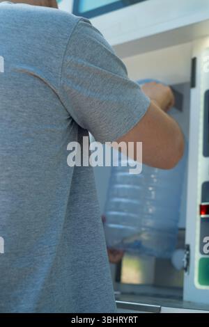 Homme au distributeur automatique d'eau propre pratiquant la routine quotidienne de soins de santé en milieu urbain. Banque D'Images