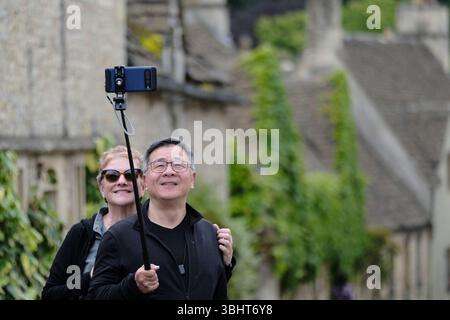 Astrtle Combe, Royaume-Uni. 11 juin 2025. Visiteurs posant. Castle Combe, a . Wiltshire village sur le bord des Cotswolds est populaire auprès des touristes du monde entier. Sur la photo sont les visiteurs d'aujourd'hui qui apprécient le village ; prendre et poser pour des photos comme si la rue principale est un plateau de cinéma, plutôt qu'à l'extérieur de la maison de quelqu'un. Crédit : JMF News/Alamy Live News Banque D'Images